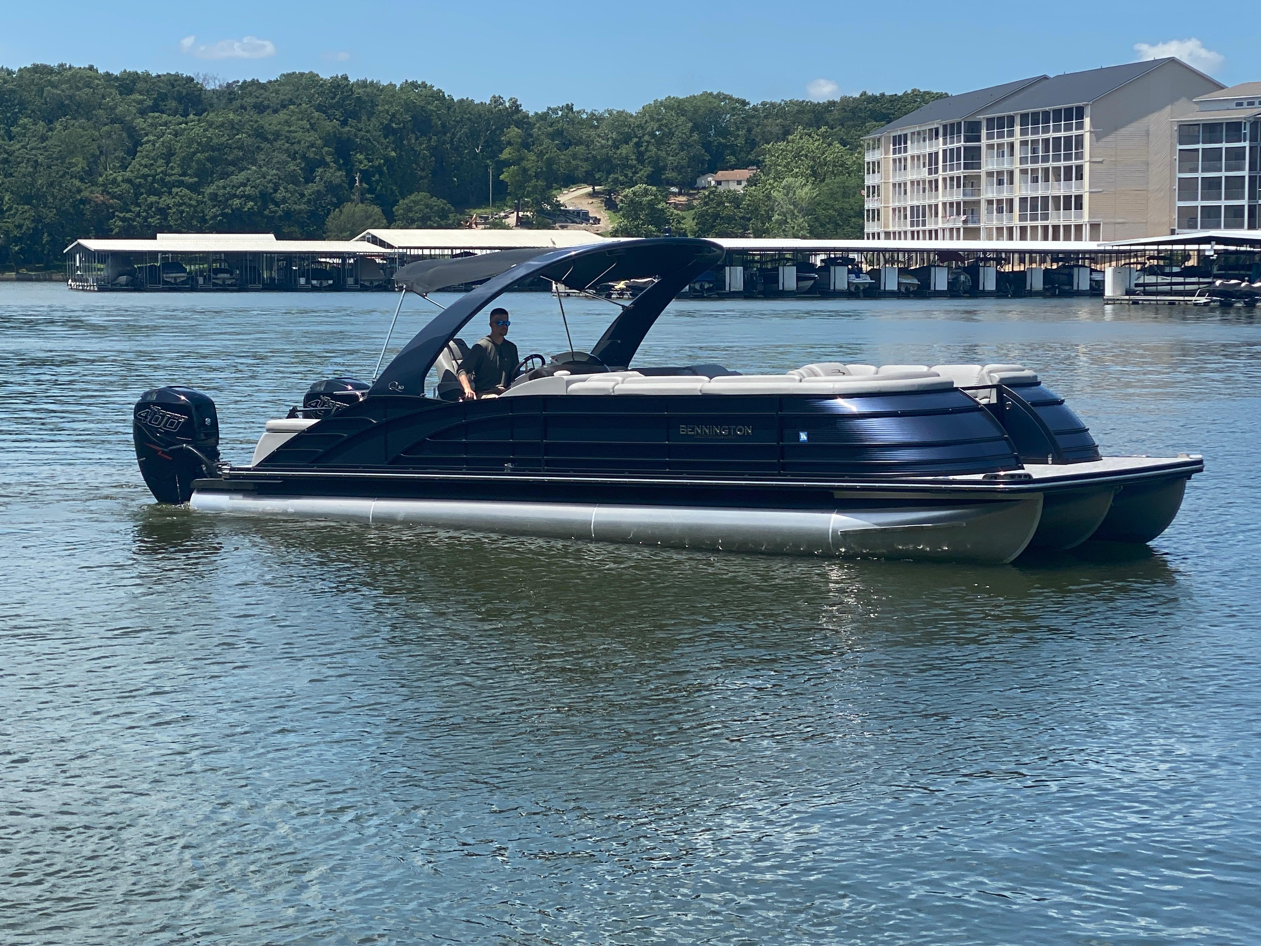 Slide: The Image of 2020 Bennington 30 QSBAX2 pontoon boat on a calm lake, with scenic background. - 2
