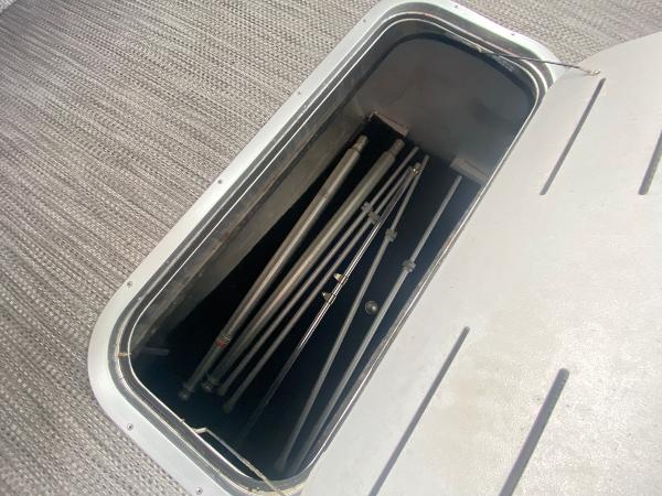 Slide: The Image of Open storage compartment on 2020 Bennington 30 QSBAX2 boat, showing metal poles inside. - 34