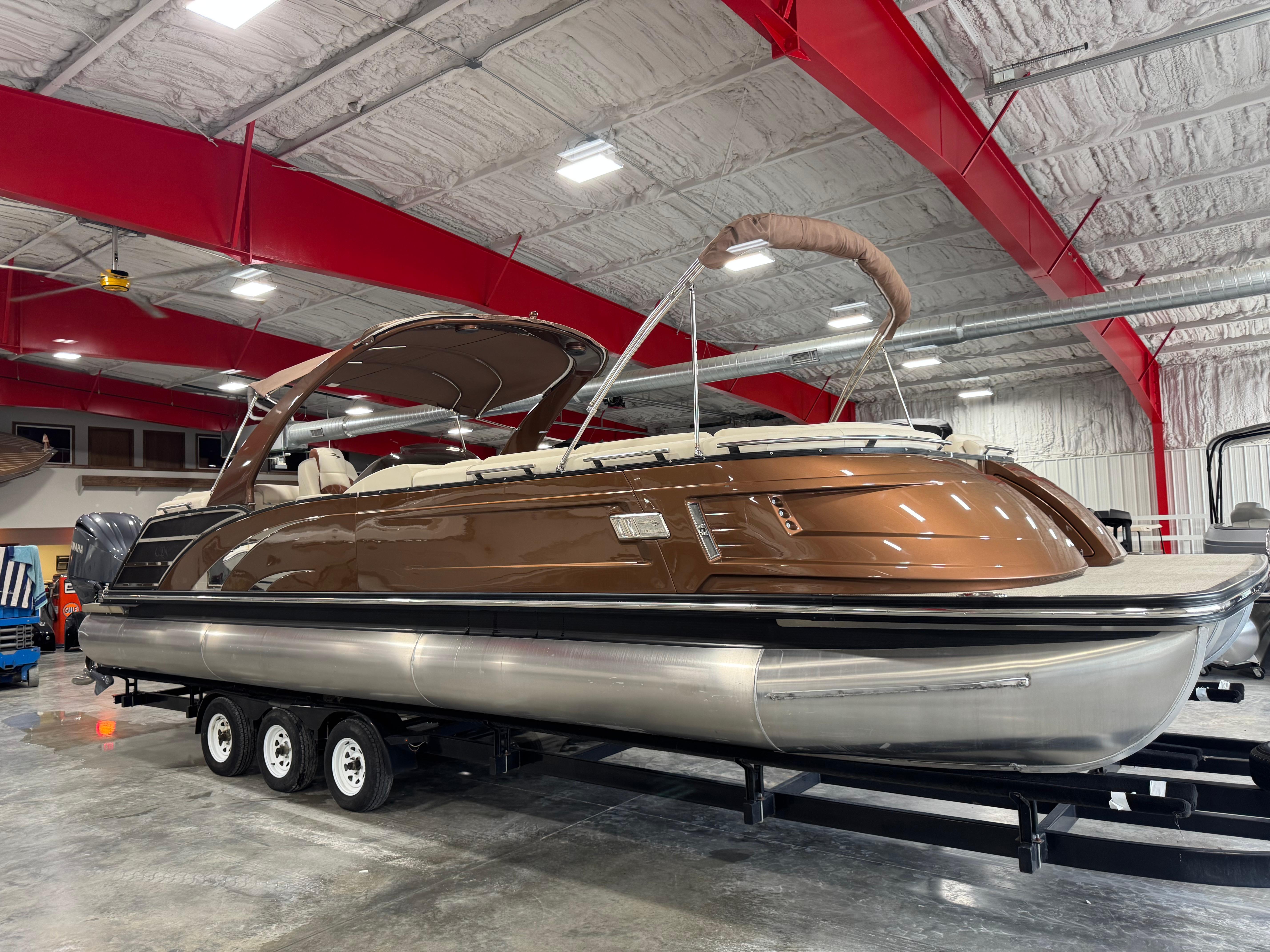 Slide: The Image of 2022 Bennington QX 30 pontoon boat in a showroom with red beams. - 2
