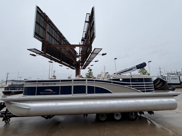 Slide: The Image of 2017 Bennington R23 pontoon boat on trailer, parked under large billboard on overcast day. - 1