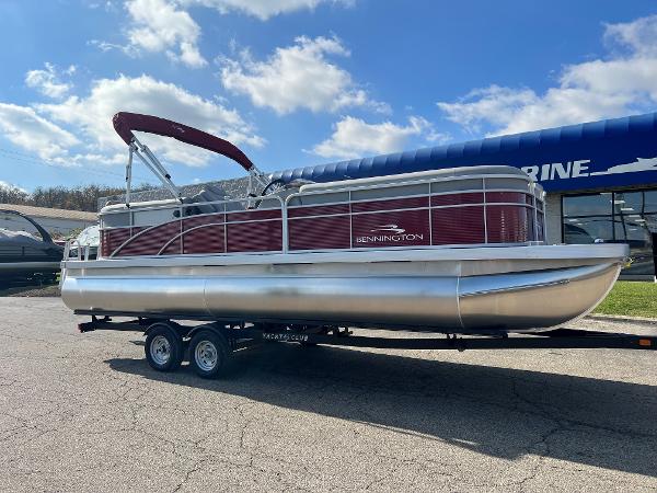 Slide: The Image of 2023 Bennington SV Line pontoon boat on a trailer under a blue sky. - 0