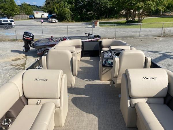 Slide: The Image of 2024 Bentley Pontoons 220 Legacy Navigator interior with beige seating and steering console. - 2