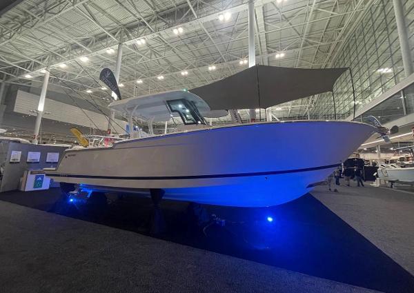 Slide: The Image of 2023 Bertram 28 CC boat displayed at an indoor boat show. - 0