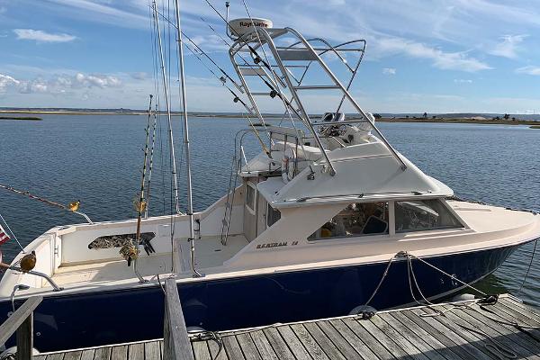 Slide: The Image of 1972 Bertram 28 Flybridge boat docked by the water on a sunny day. - 0
