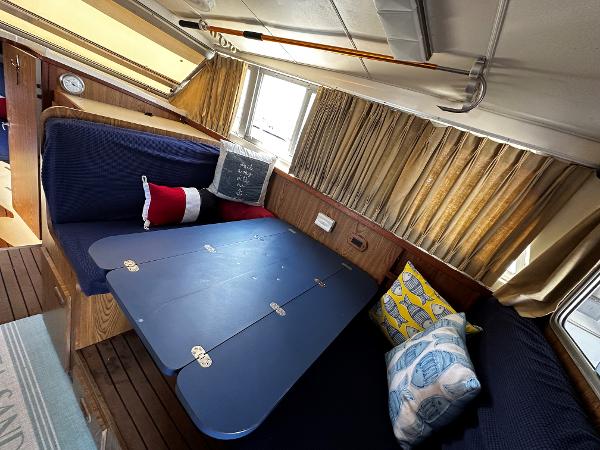 Slide: The Image of Interior of 1980 Bertram 33 Sport Fisherman with blue seating and foldable table. - 14