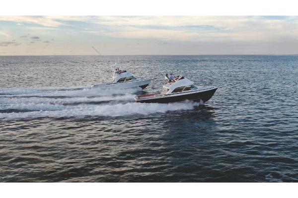 Slide: The Image of Two 2023 Bertram 35 Flybridge boats cruising on open water at sunset. - 1