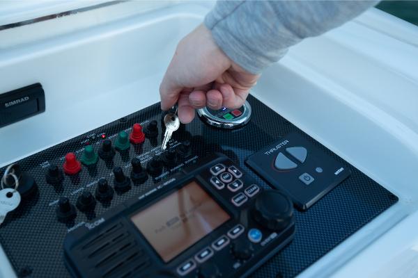 Slide: The Image of Hand starting the control panel of a 2023 Bertram 35 Flybridge boat. - 13