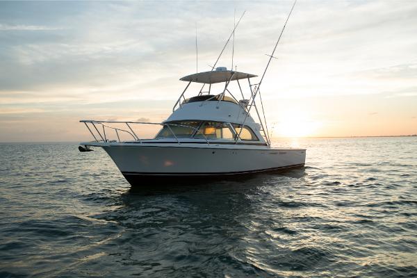 Slide: The Image of 2023 Bertram 35 Flybridge boat on calm water at sunset. - 21