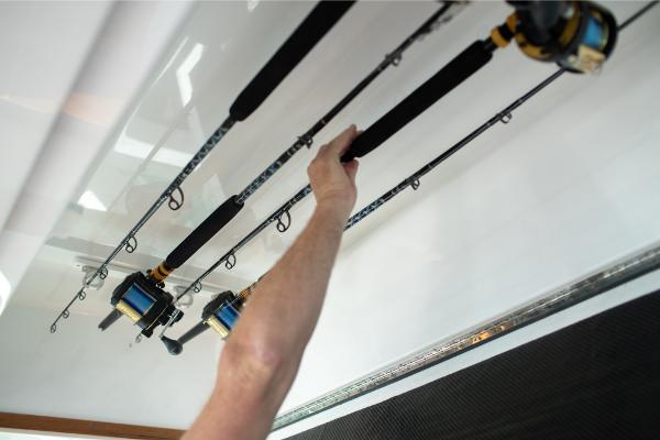 Slide: The Image of Person reaching for fishing rods on a 2023 Bertram 35 Flybridge boat. - 31