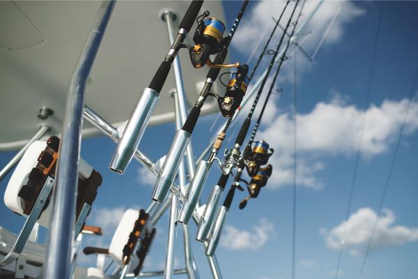 Slide: The Image of Fishing rods on a 2023 Bertram 35 Flybridge boat under a clear blue sky. - 37