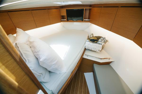 Slide: The Image of 2023 Bertram 35 Flybridge cabin with bed, pillows, and wooden cabinetry. - 5