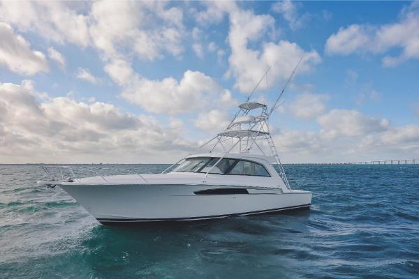 Slide: The Image of 2023 Bertram 50 Sport yacht cruising on open water under a partly cloudy sky. - 1