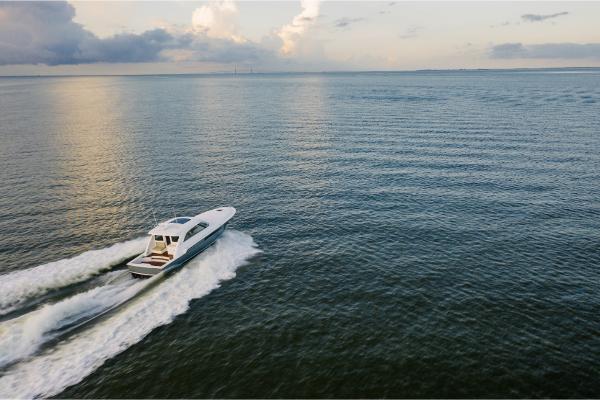 Slide: The Image of 2023 Bertram 50 Sport yacht cruising on open water at sunset. - 16