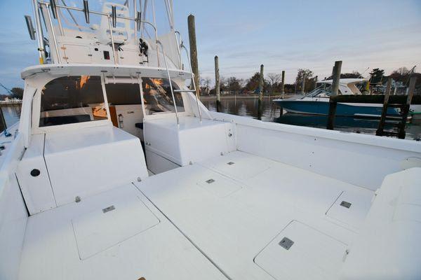 Slide: The Image of 1965 Bertram Sportfisher boat docked, showcasing spacious deck and fishing amenities. - 12