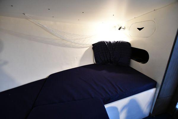 Slide: The Image of 1965 Bertram Sportfisher cabin interior with navy bedding and wall lighting. - 21