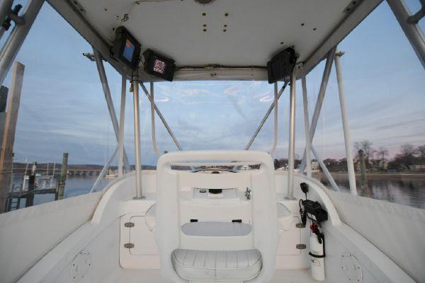Slide: The Image of 1965 Bertram Sportfisher boat cockpit with steering wheel, docked by calm waters. - 23