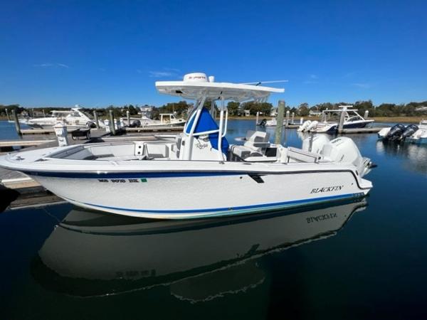 Slide: The Image of 2019 Blackfin 242 CC boat docked in a marina on a sunny day. - 0