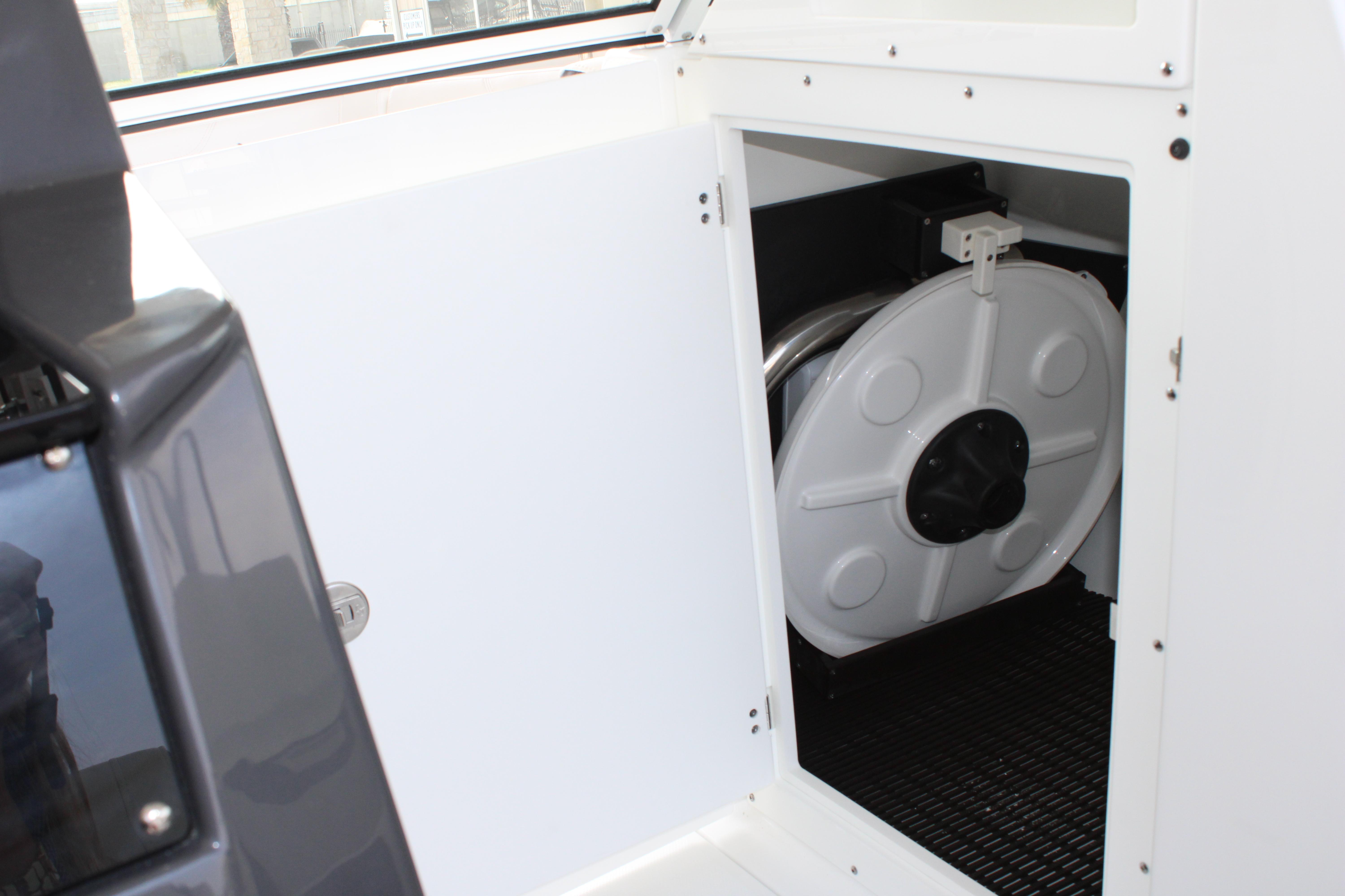 Slide: The Image of Storage compartment on a 2023 Blackfin 252 DC boat, featuring a neatly stored hose reel. - 35