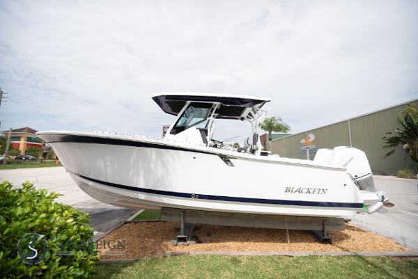 Slide: The Image of 2024 Blackfin 272 CC boat displayed outdoors on a stand. - 0