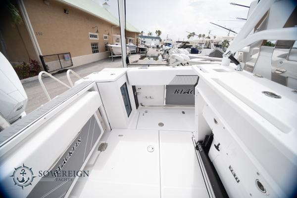 Slide: The Image of 2024 Blackfin 272 CC boat interior at a marina, showcasing spacious deck and seating. - 29