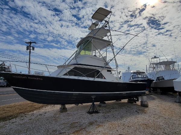 Slide: The Image of 1980 Blackfin 32 Flybridge boat on dry dock under a partly cloudy sky. - 0