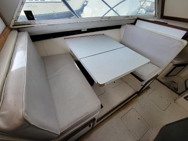 Slide: The Image of 1980 Blackfin 32 Flybridge interior seating area with white cushions and table. - 11