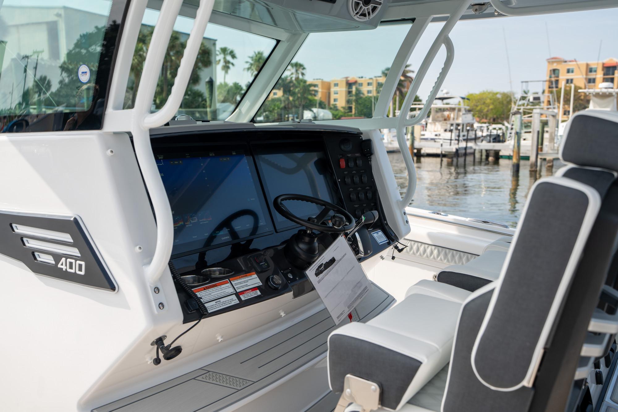Slide: The Image of 2024 Blackfin 400 CC boat cockpit with modern controls and dual screens at a marina. - 16