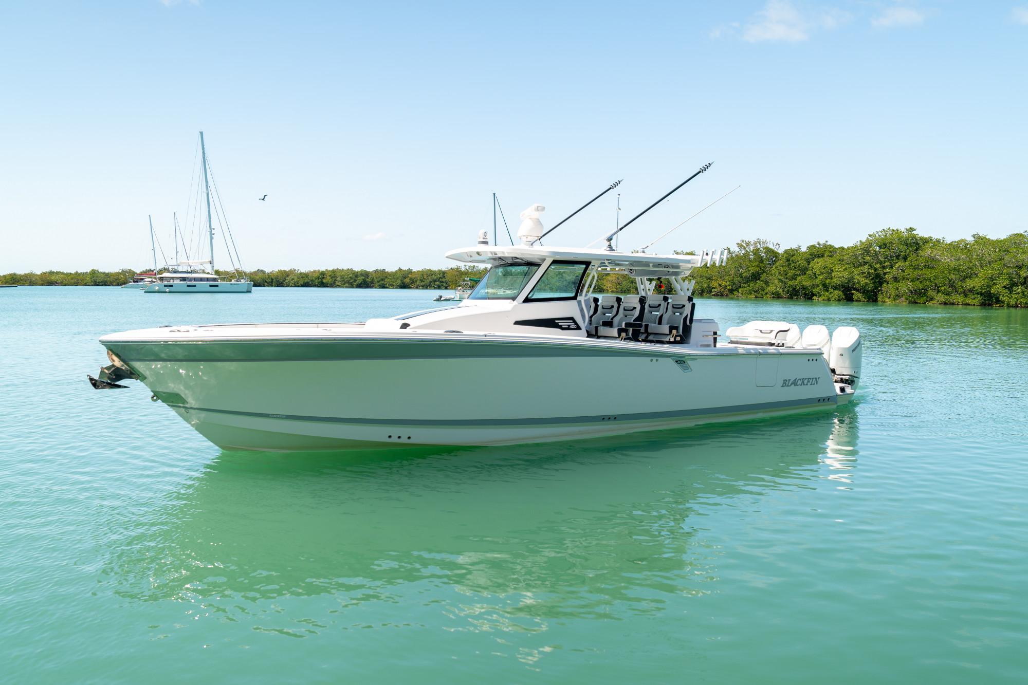 Slide: The Image of 2024 Blackfin 400 CC boat on calm water, clear sky, and lush background. - 2