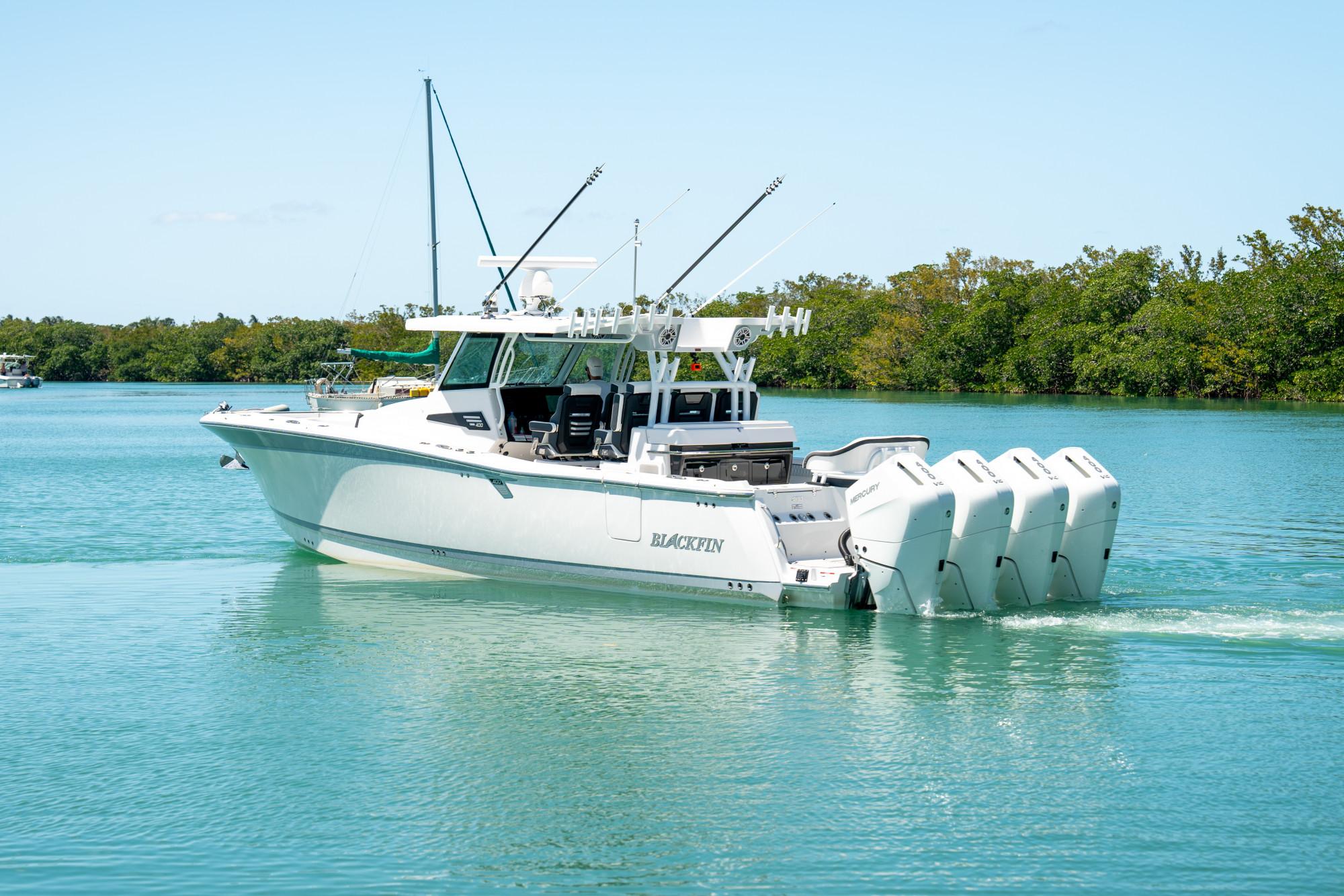 Slide: The Image of 2024 Blackfin 400 CC boat cruising on calm water with lush greenery in the background. - 5