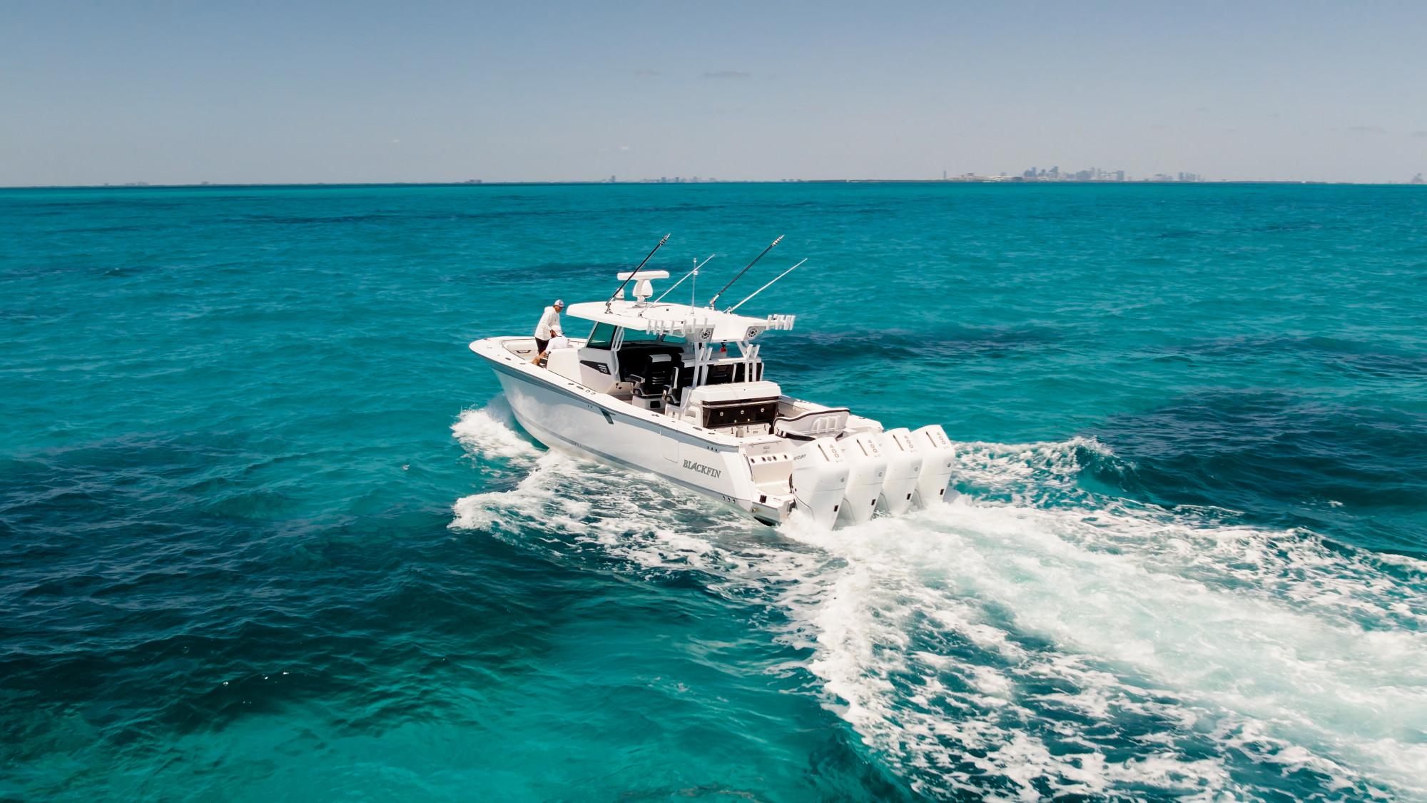 Slide: The Image of 2024 Blackfin 400 CC boat cruising on clear turquoise ocean waters. - 9