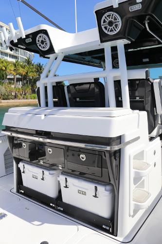 Slide: The Image of 2025 Blackfin 400 CC boat with modern seating and storage, docked near tropical scenery. - 11