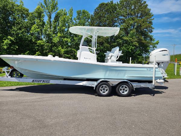 Slide: The Image of 2025 BlackJack 256 Coastal boat on trailer, parked outdoors with trees in background. - 0
