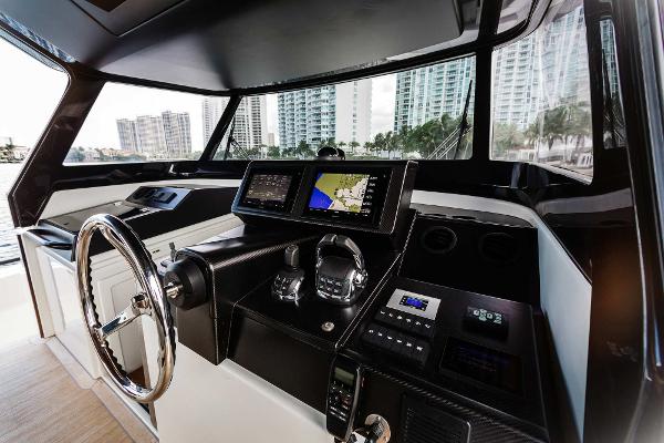 Slide: The Image of 2019 Bluegame BG62 yacht helm with modern navigation equipment and cityscape view. - 17