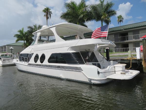 Slide: The Image of Bluewater 5800 yacht docked at marina with American flag, palm trees, and buildings in the background. - 11