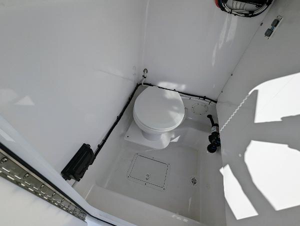 Slide: The Image of 2024 Bluewater Sportfishing 2850 boat interior bathroom with white marine toilet. - 16