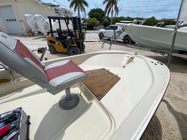 Slide: The Image of 1976 Boston Whaler 150 Sport boat with red and white seating, docked near forklift. - 11