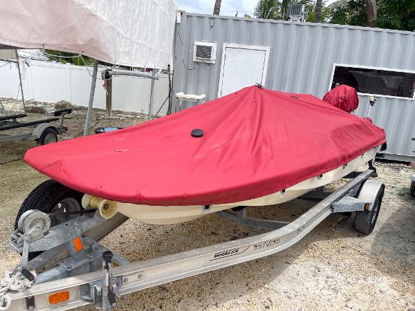 Slide: The Image of 1976 Boston Whaler 150 Sport boat with red cover on trailer. - 14
