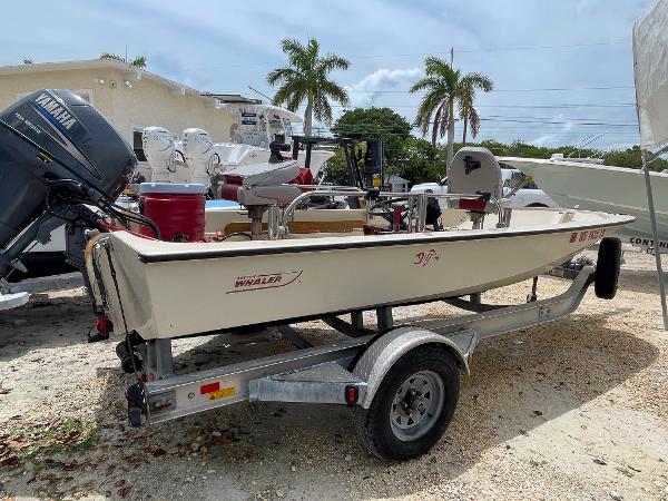 Slide: The Image of 1976 Boston Whaler 150 Sport boat on trailer, parked outdoors with palm trees in background. - 4
