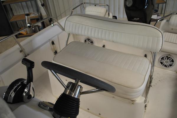 Slide: The Image of 2001 Boston Whaler 16 Dauntless boat interior with white cushioned seating and steering console. - 12