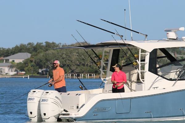 Slide: The Image of Two people fishing on a 2023 Boston Whaler 325 Conquest boat. - 2