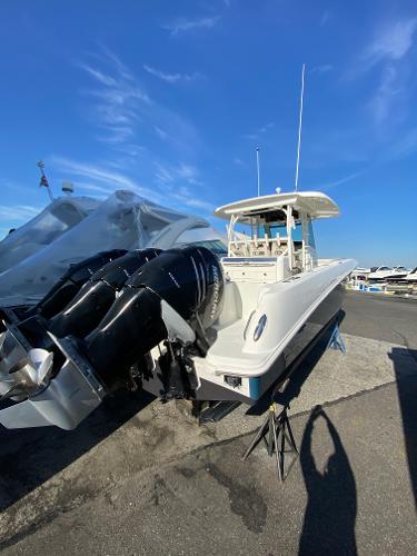 Slide: The Image of 2017 Boston Whaler 350 Outrage boat with triple engines, docked under a clear blue sky. - 31