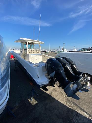 Slide: The Image of 2017 Boston Whaler 350 Outrage boat with triple outboard engines, docked under clear blue sky. - 32
