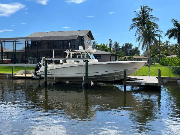 Slide: The Image of 2013 Boston Whaler 370 Outrage docked by a waterfront home with palm trees. - 1