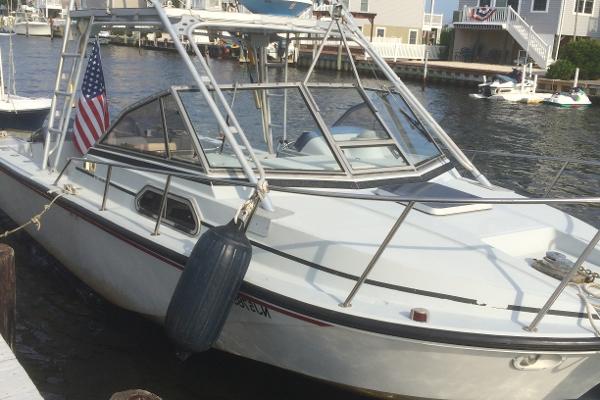 Slide: The Image of 1987 Boston Whaler Cuddy Tower boat docked by waterfront homes, featuring American flag. - 0