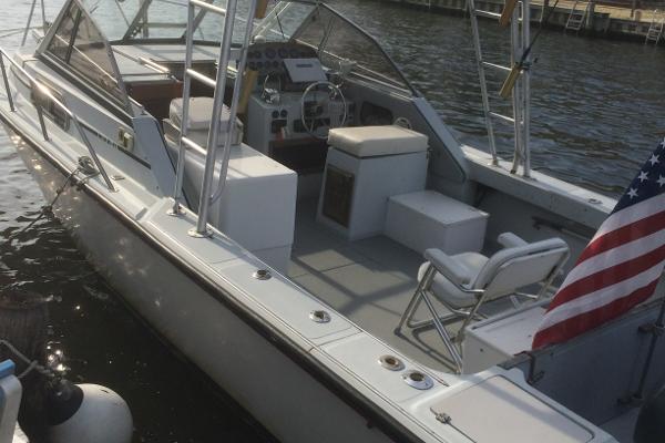 Slide: The Image of 1987 Boston Whaler Cuddy Tower boat docked, featuring spacious seating and American flag. - 1