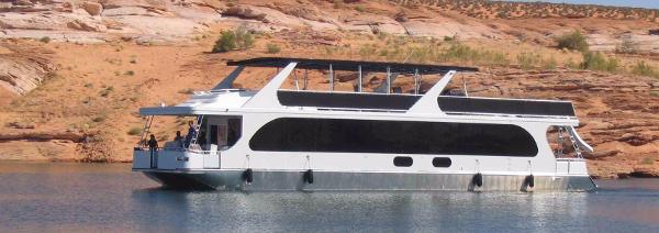 Slide: The Image of 2010 Bravada Houseboat Dream Catcher SHARE #16 on a serene lake with rocky shoreline. - 1