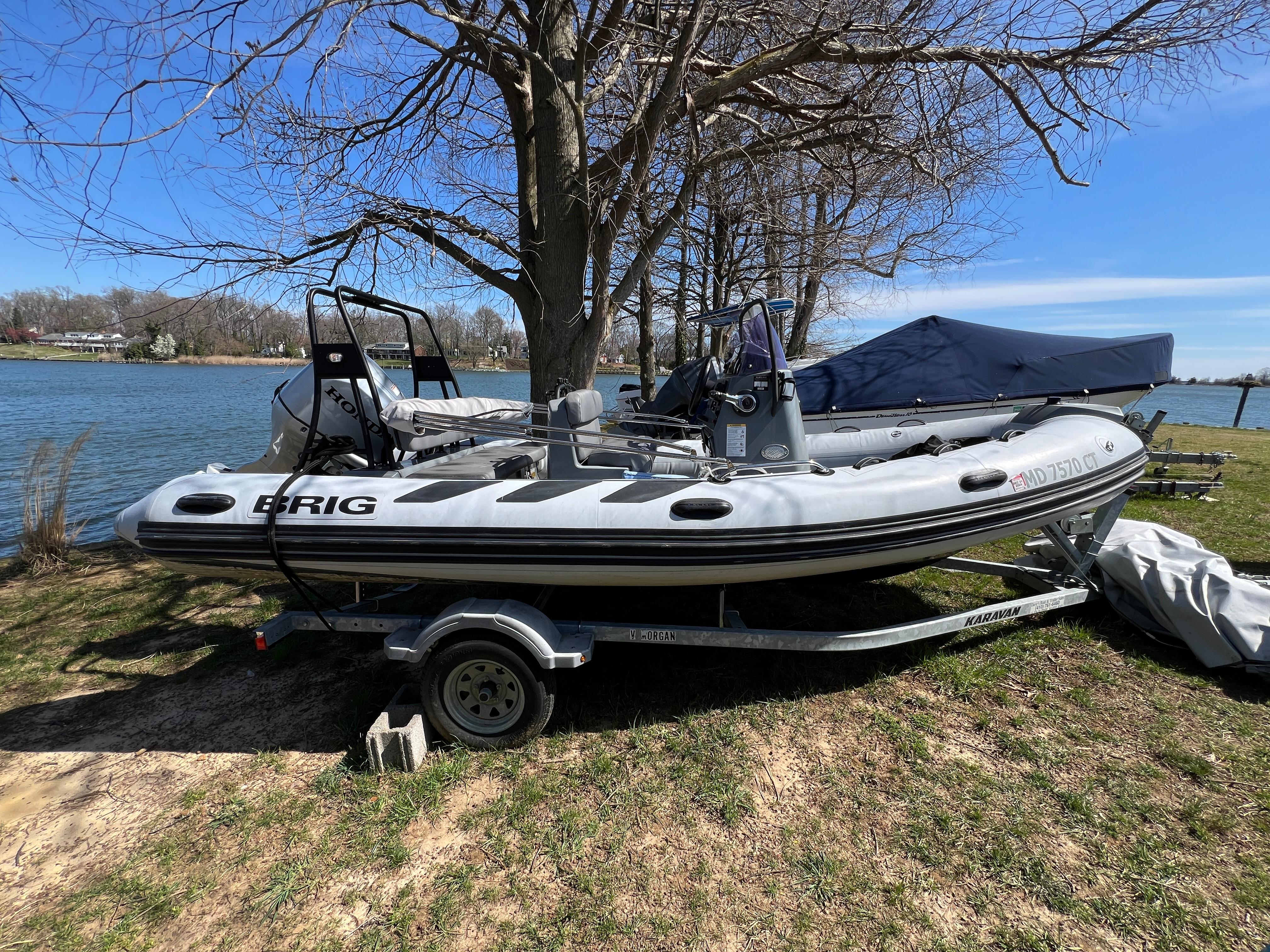 Slide: The Image of 2021 Brig Inflatables Navigator 520 boat on a trailer by a lake. - 0