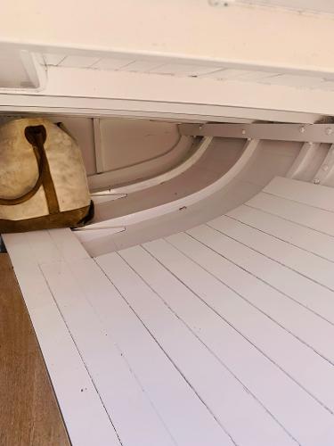 Slide: The Image of Interior of a 1914 Buzzards Bay 25 boat with white wooden planks and a vintage bag. - 12