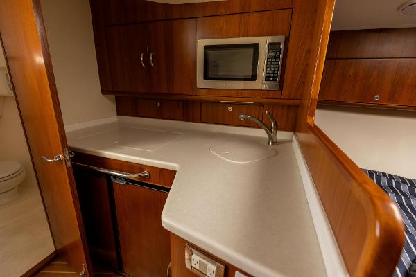 Slide: The Image of 2013 Cabo 36 Express yacht kitchen with microwave, sink, and wooden cabinetry. - 17