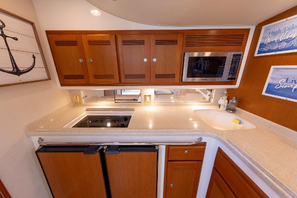 Slide: The Image of 2005 Cabo 40 Express yacht kitchen with wooden cabinets, microwave, and modern appliances. - 26